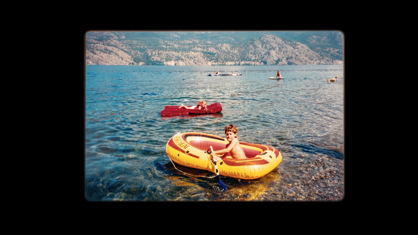 Vintage photo of a boy in a yellow inflatable raft on a lake
